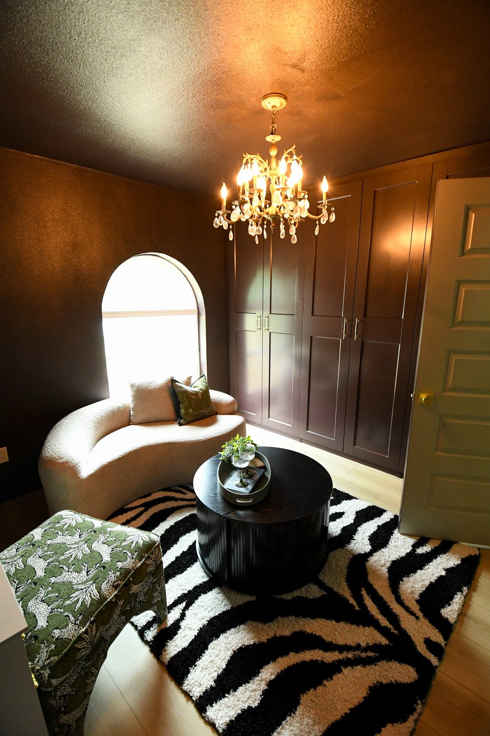 The room from the door with the curved sofa in the arched window and a zebra rug