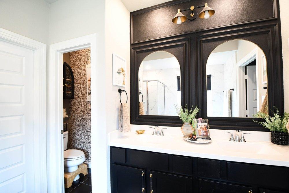 The vanity, arched mirrors and open door to the water closet