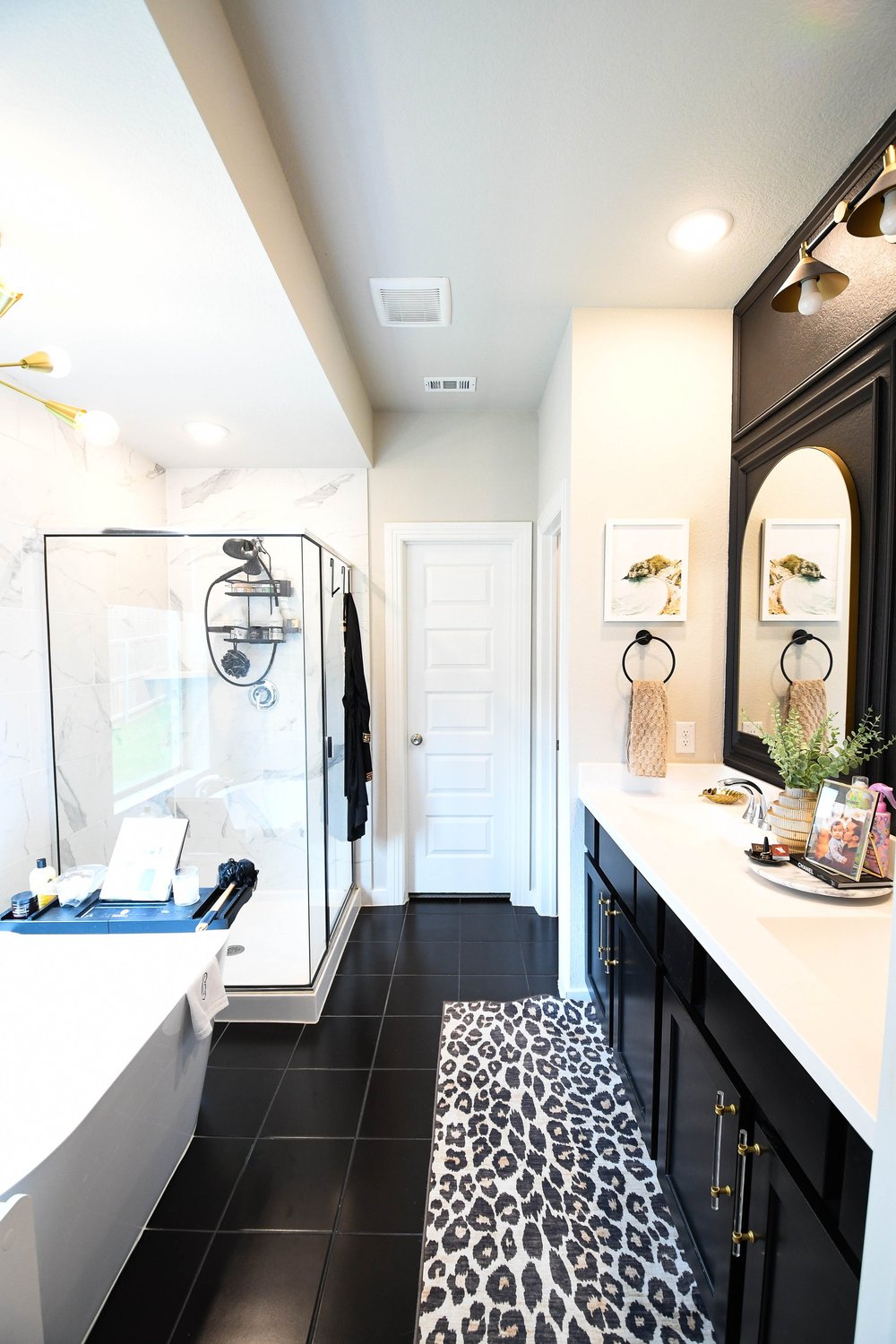 The bathroom lengthwise with the soaking tub, glass shower and black vanity run