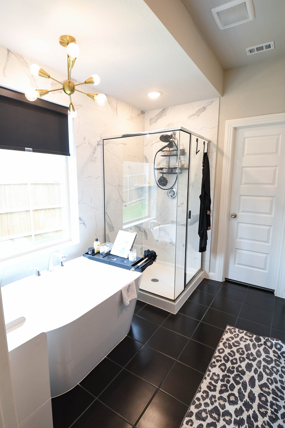 The tub and shower under a brass sputnik chandelier
