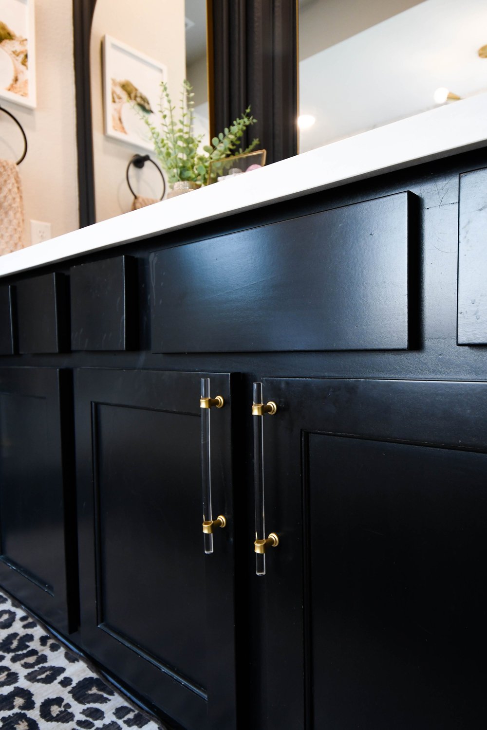 Close view of the black shaker vanity doors with brass and lucite pulls