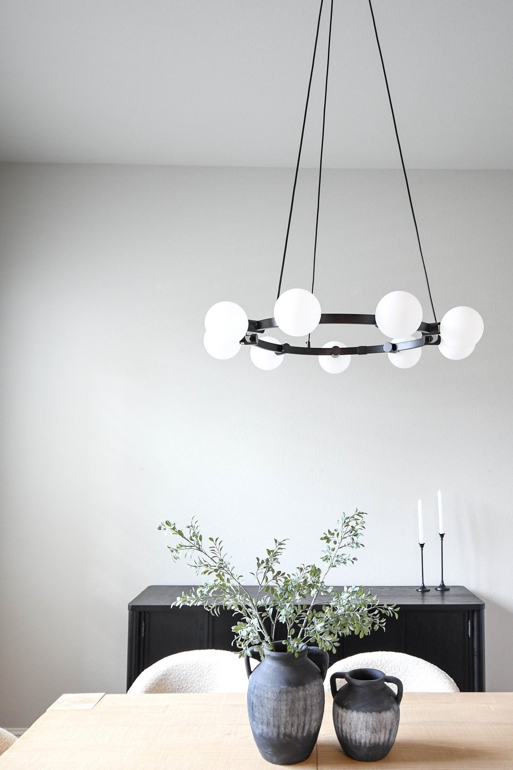 Ring chandelier with opal globes above the dining table and a black sideboard
