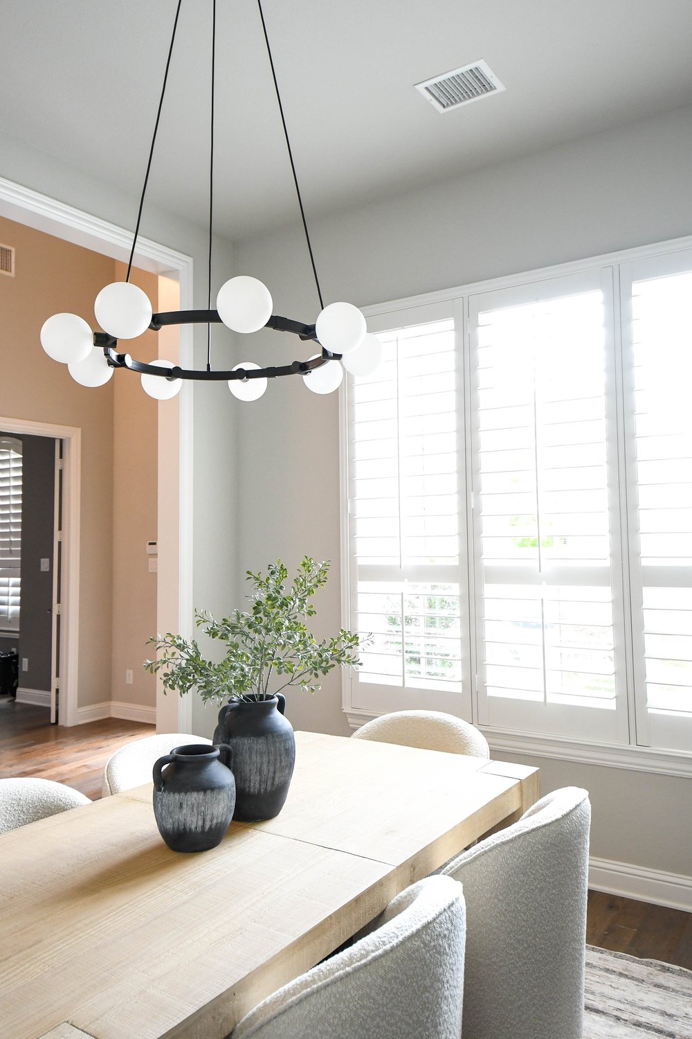 Dining room looking toward the shuttered window, table set with black vases