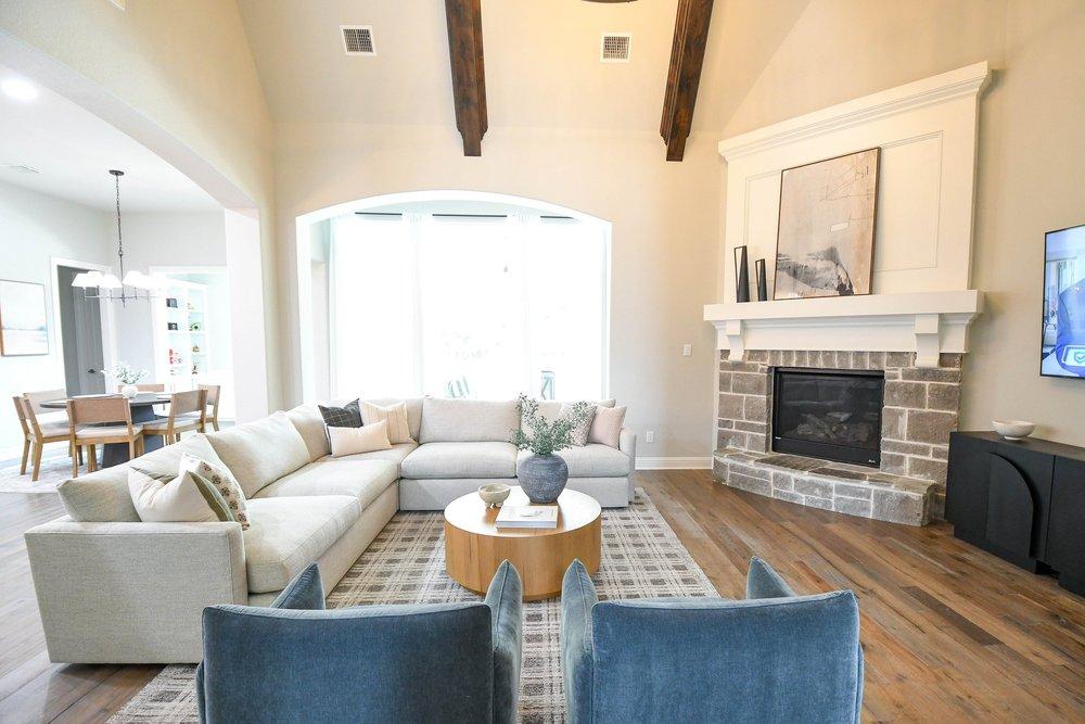 Great room from above with the sectional, blue swivel chairs and stone fireplace