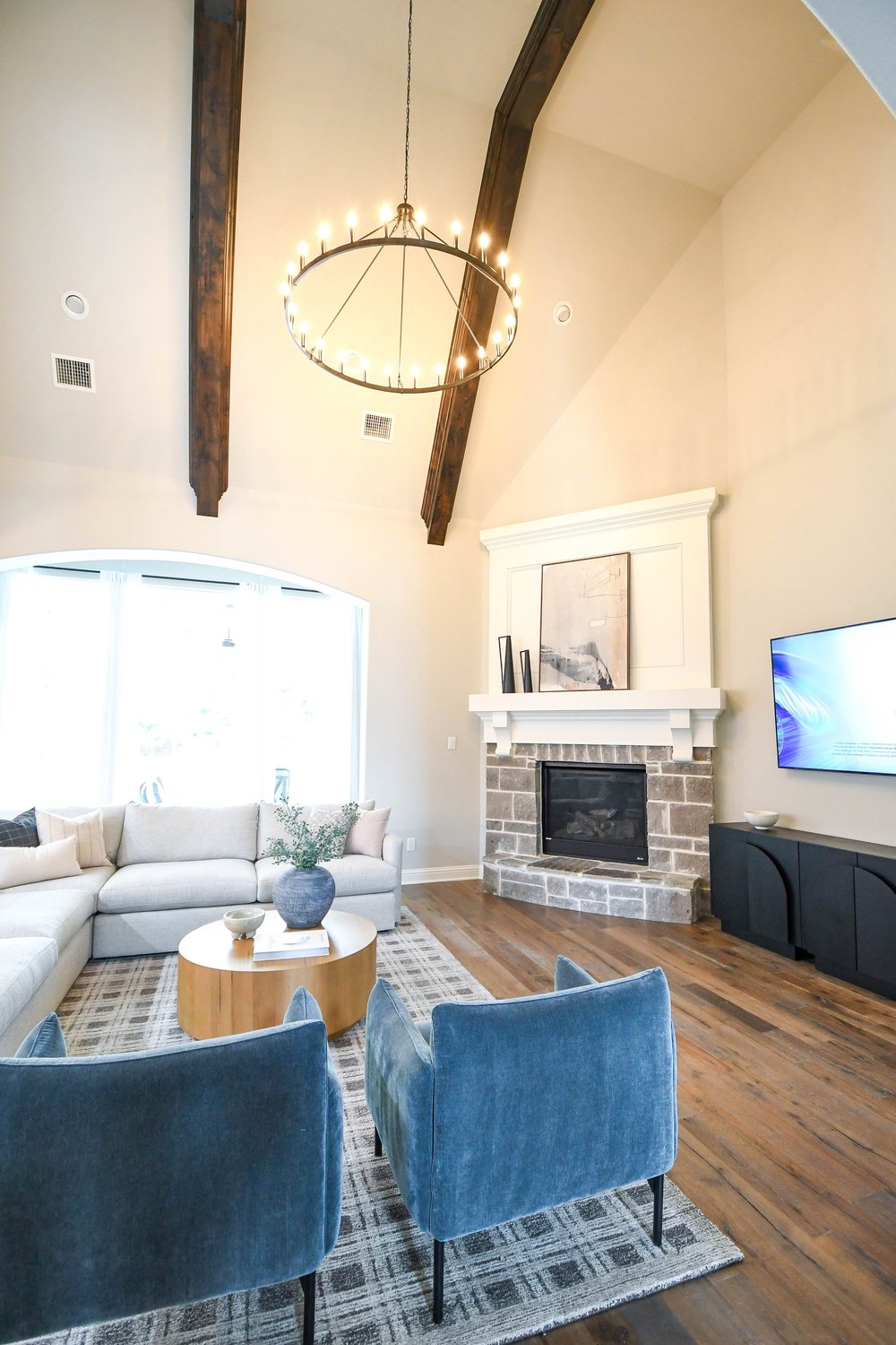 Vaulted great room with exposed beams, the fireplace and a wall mounted TV