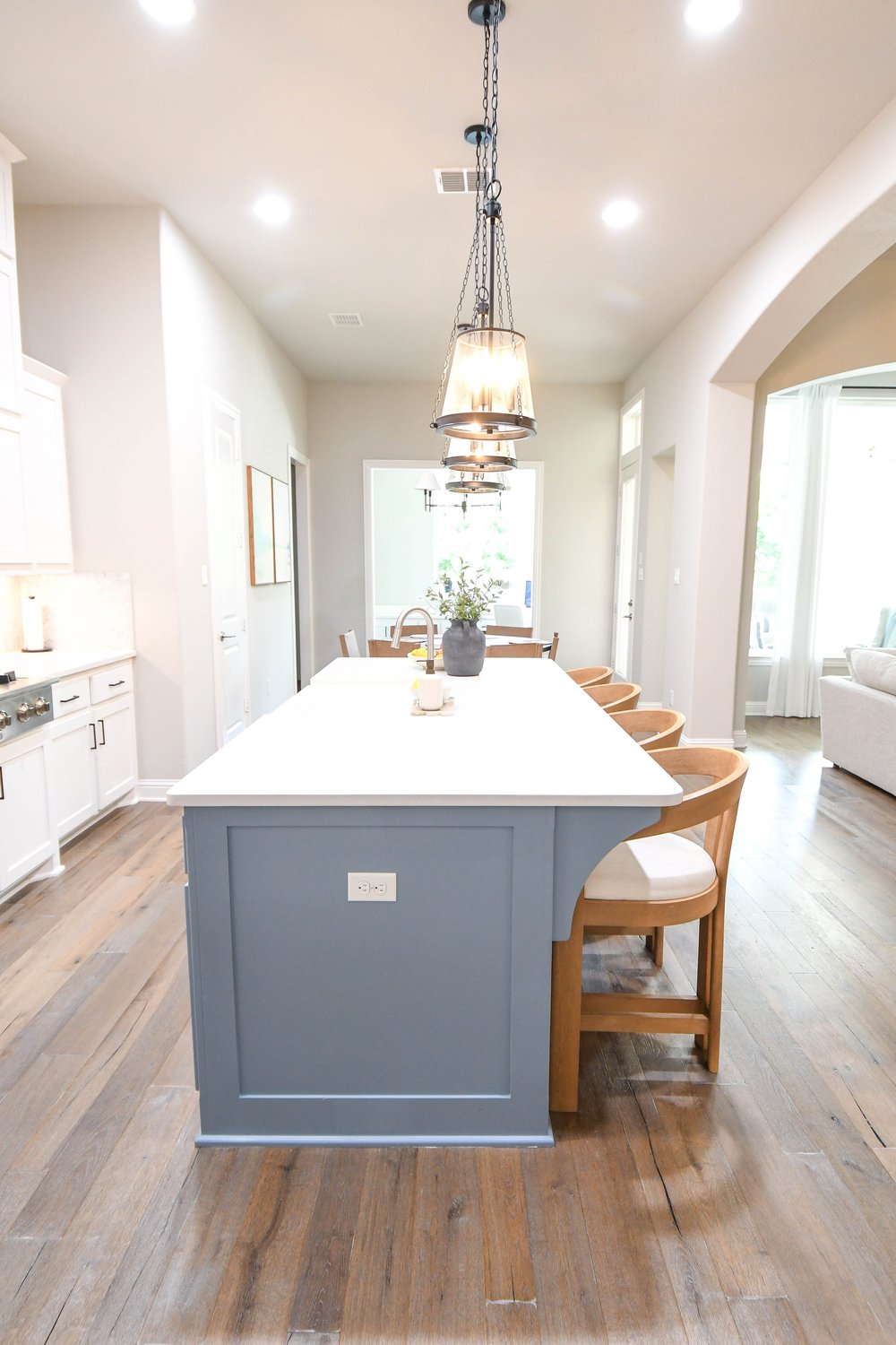 The island's blue grey base and quartz top running down the open plan