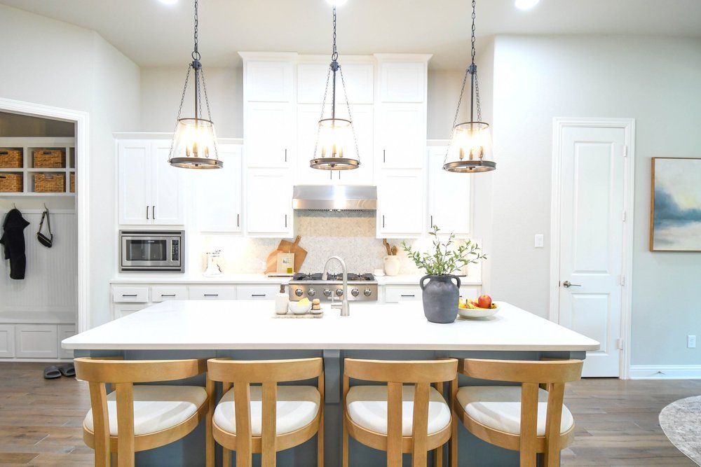 White kitchen with the range hood and island seating from the mudroom side