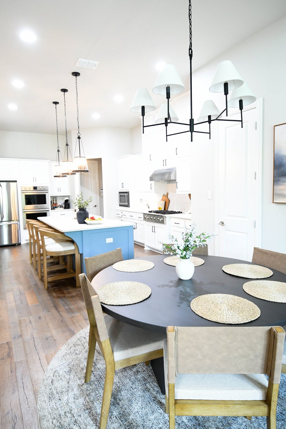 Breakfast table in the foreground with the kitchen and blue island behind