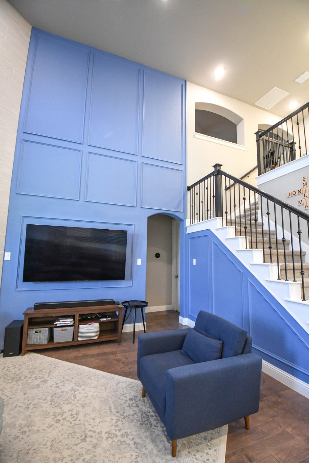 The TV wall, console and blue armchairs against the panelled blue wall