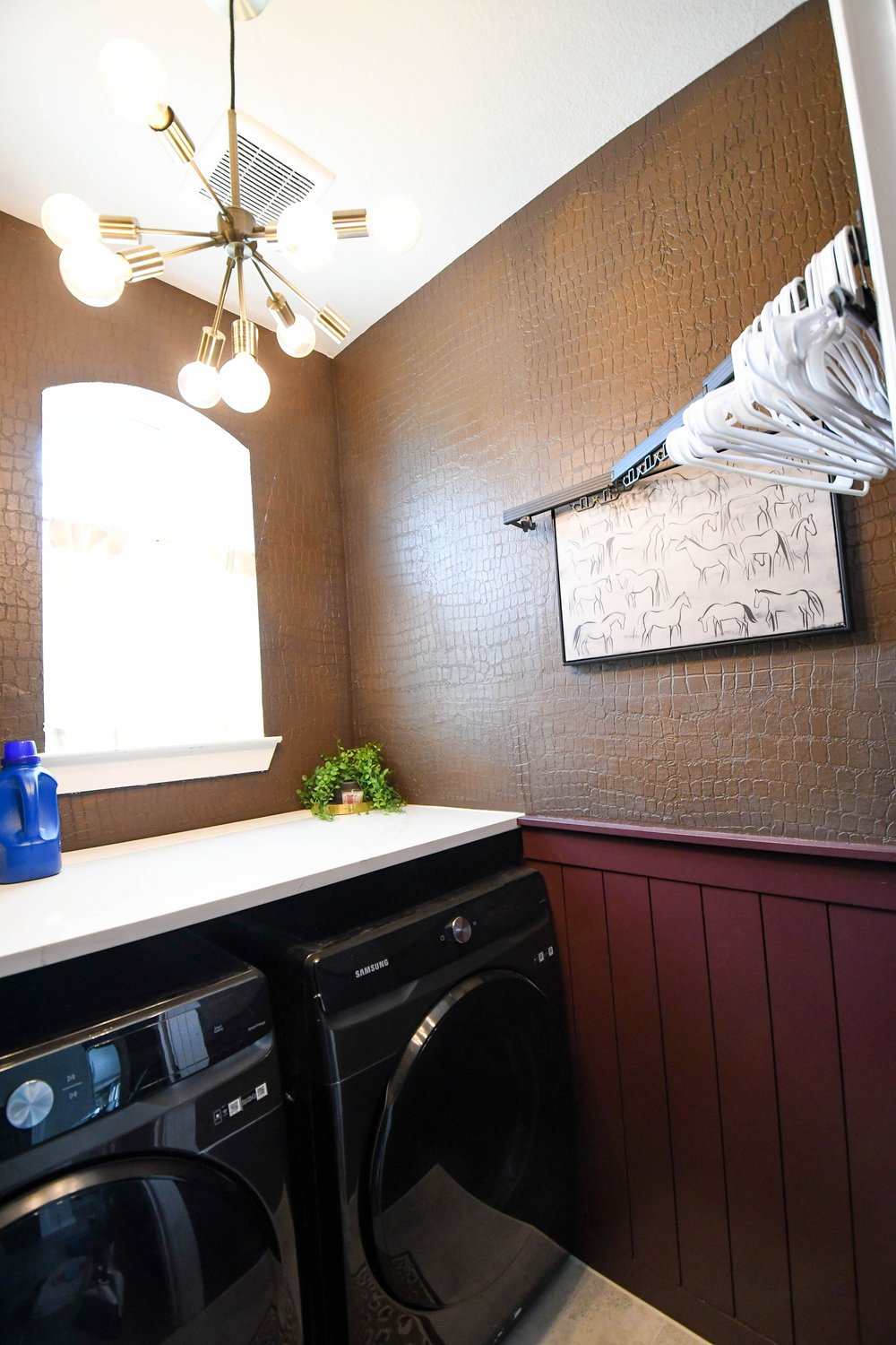 Black washer and dryer under a quartz counter with a hanging rail above