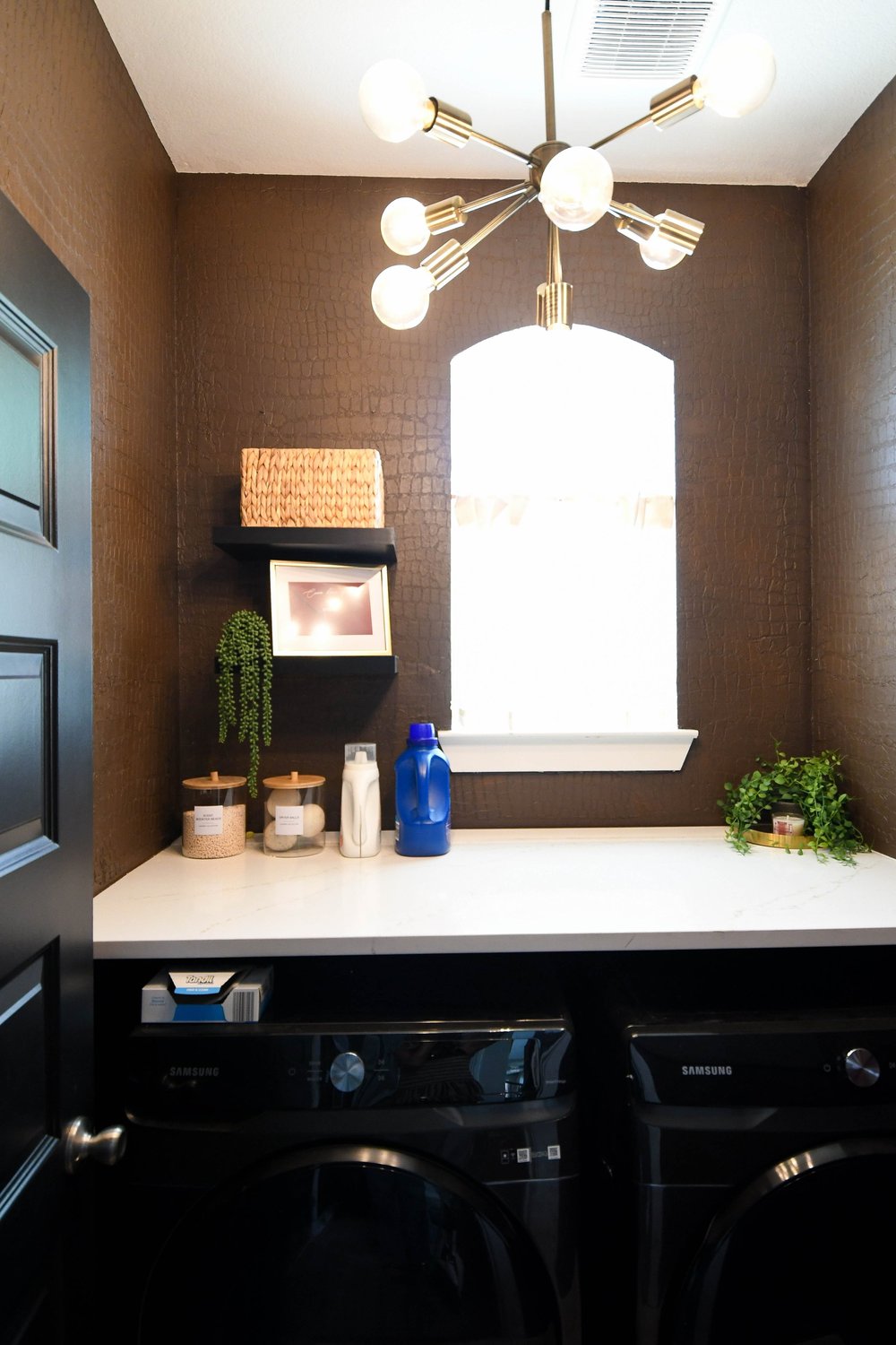 The laundry counter and machines under the brass fixture from the doorway