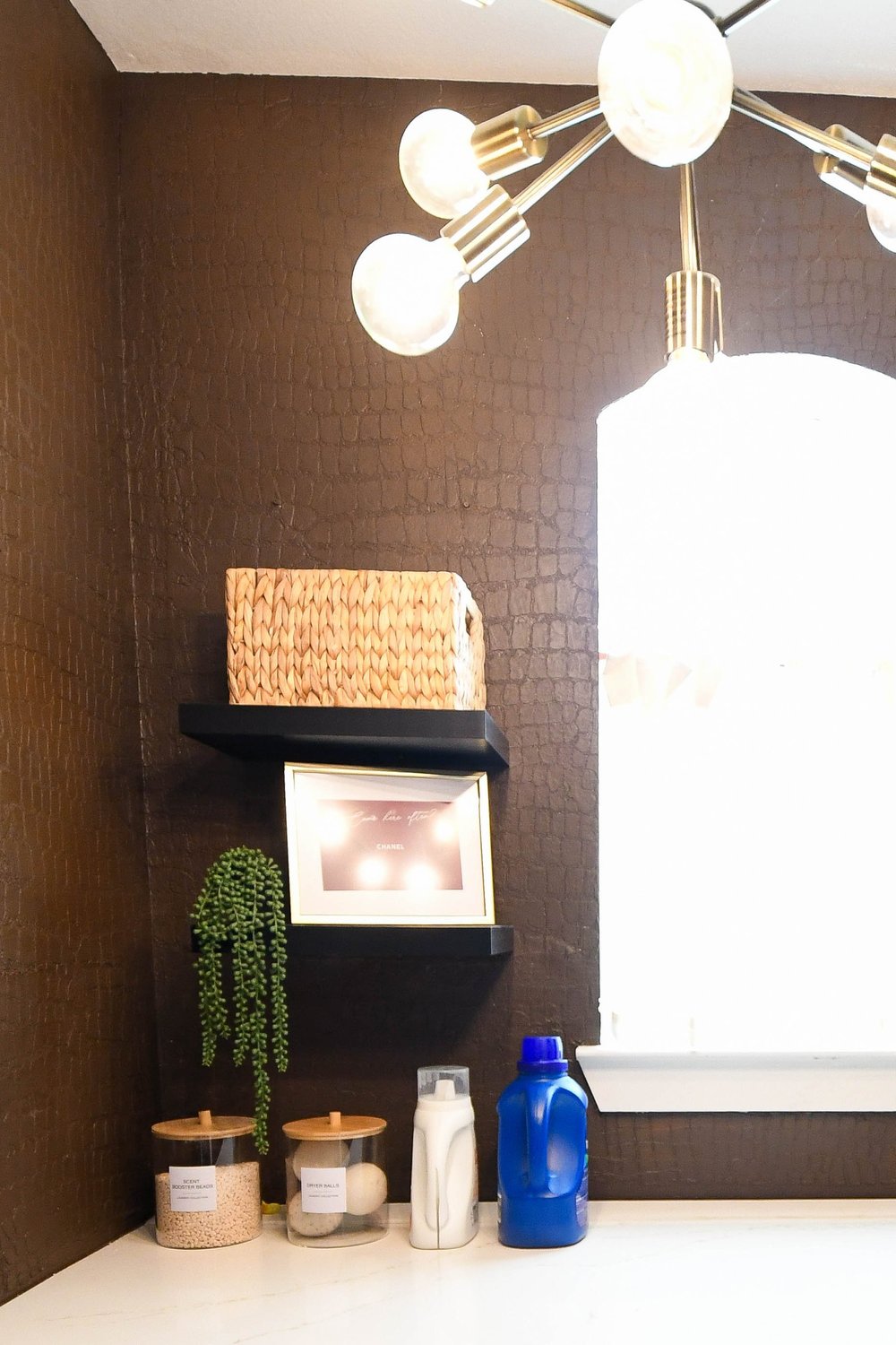 Open shelf, framed art and detergent jars on the counter by the window