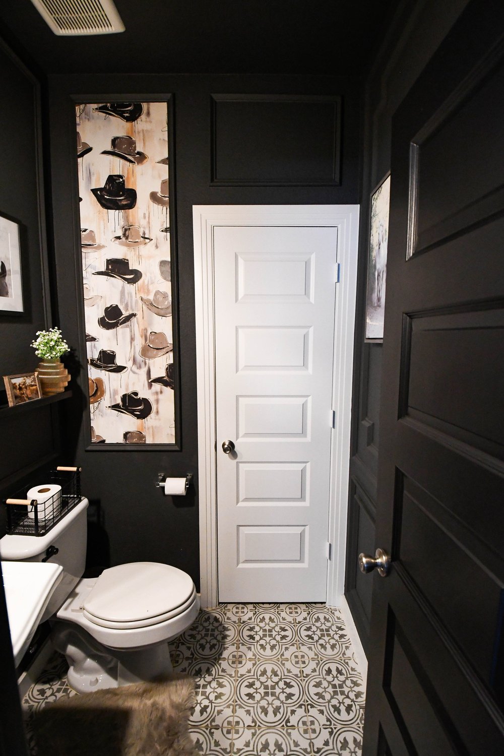 Powder bath looking to the door with patterned tile floor and wallpapered panel