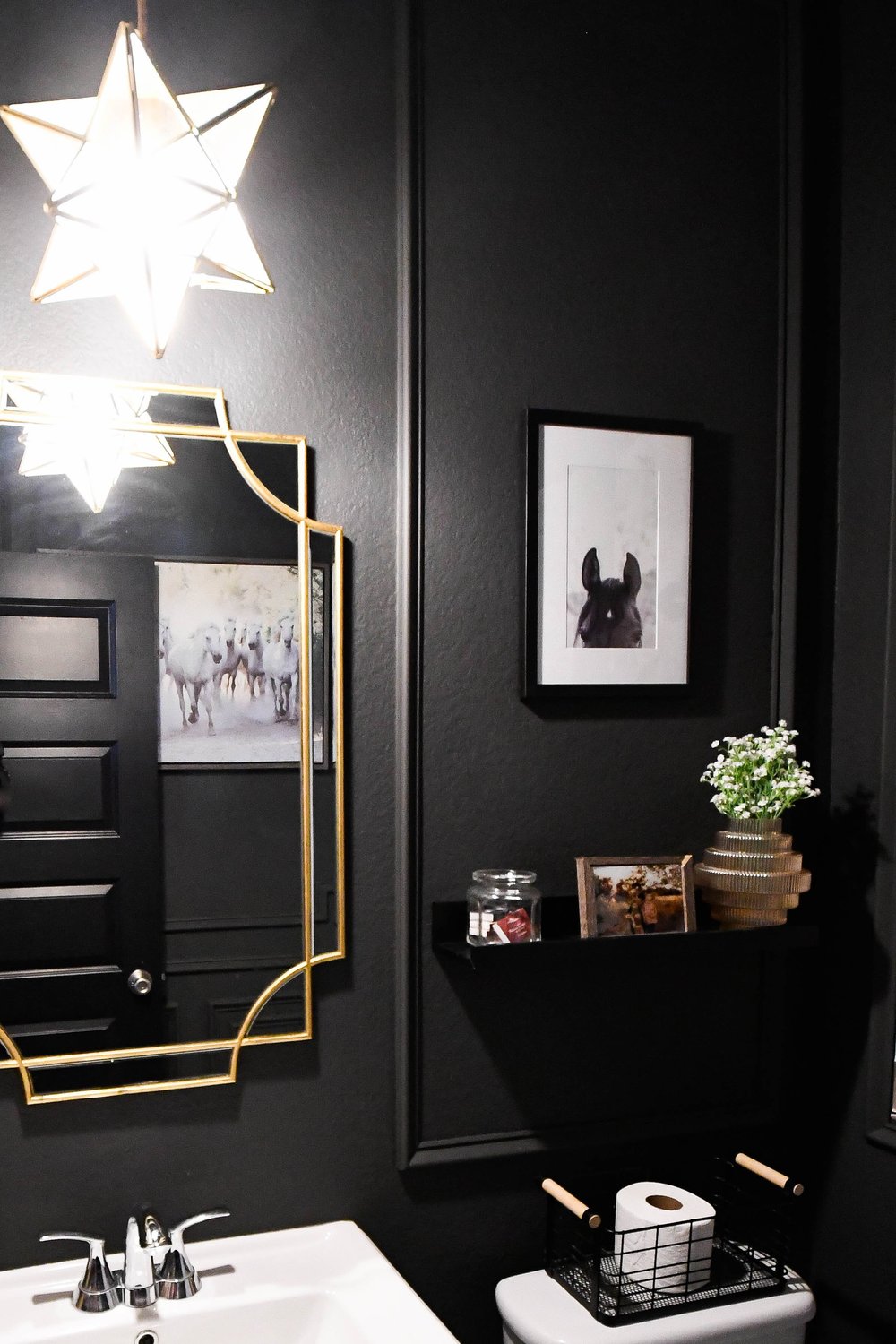 Gold trimmed mirror and framed prints on the black powder bath wall