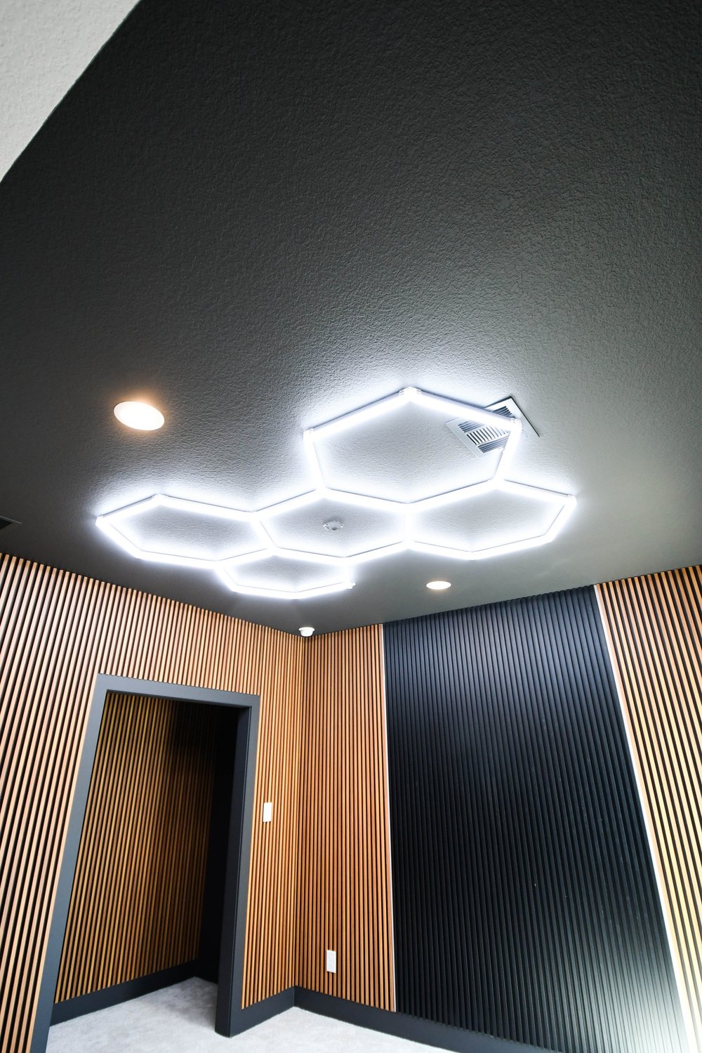 The hexagon lighting and slat wall meeting the doorway in the corner