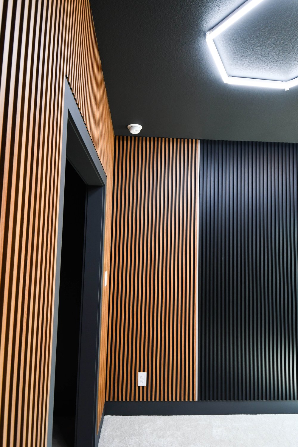 Wood slat panelling running past the doorway with the hexagon lights above