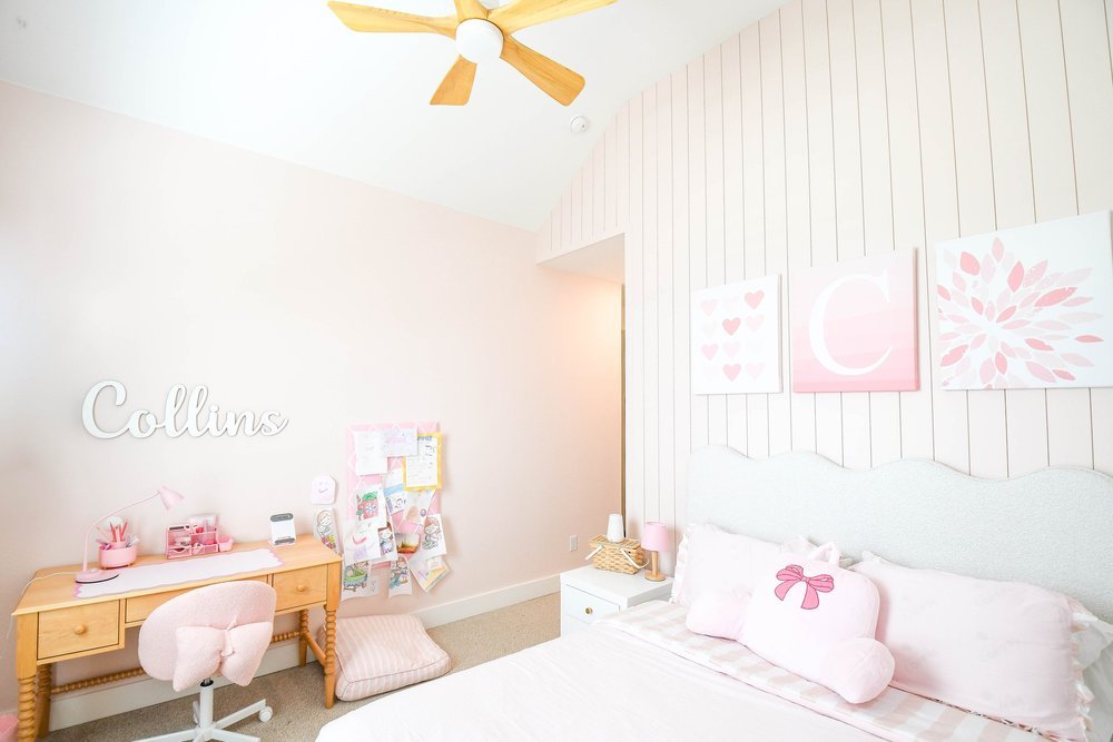 The bedroom with a wood desk, name sign and the bed under monogrammed art