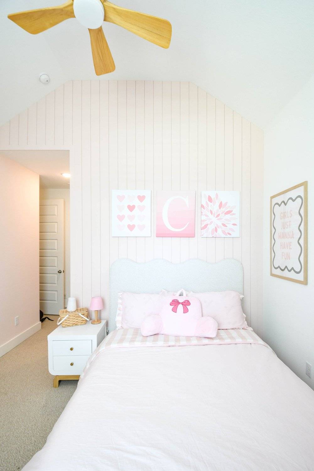 The bed on the plank wall seen down the length of the room