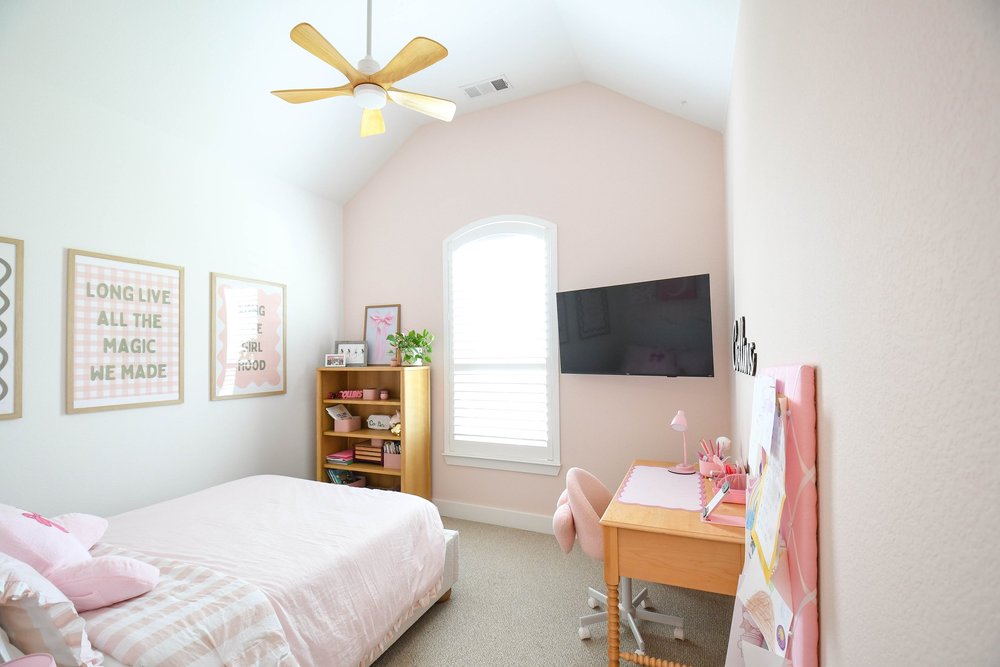 The bedroom's far wall with framed prints, bookcase and window