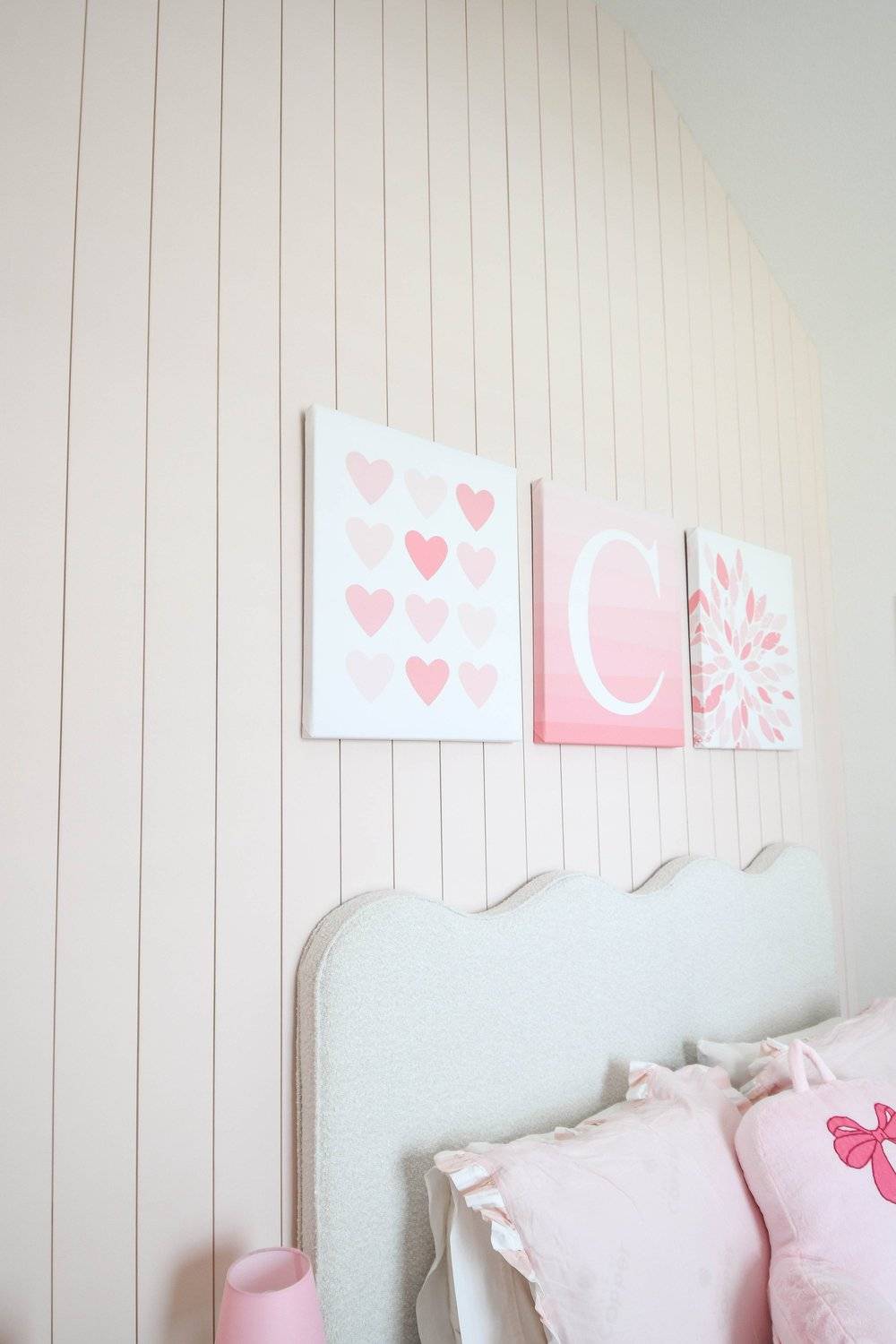 The three canvases on the vertical planking above the scalloped headboard
