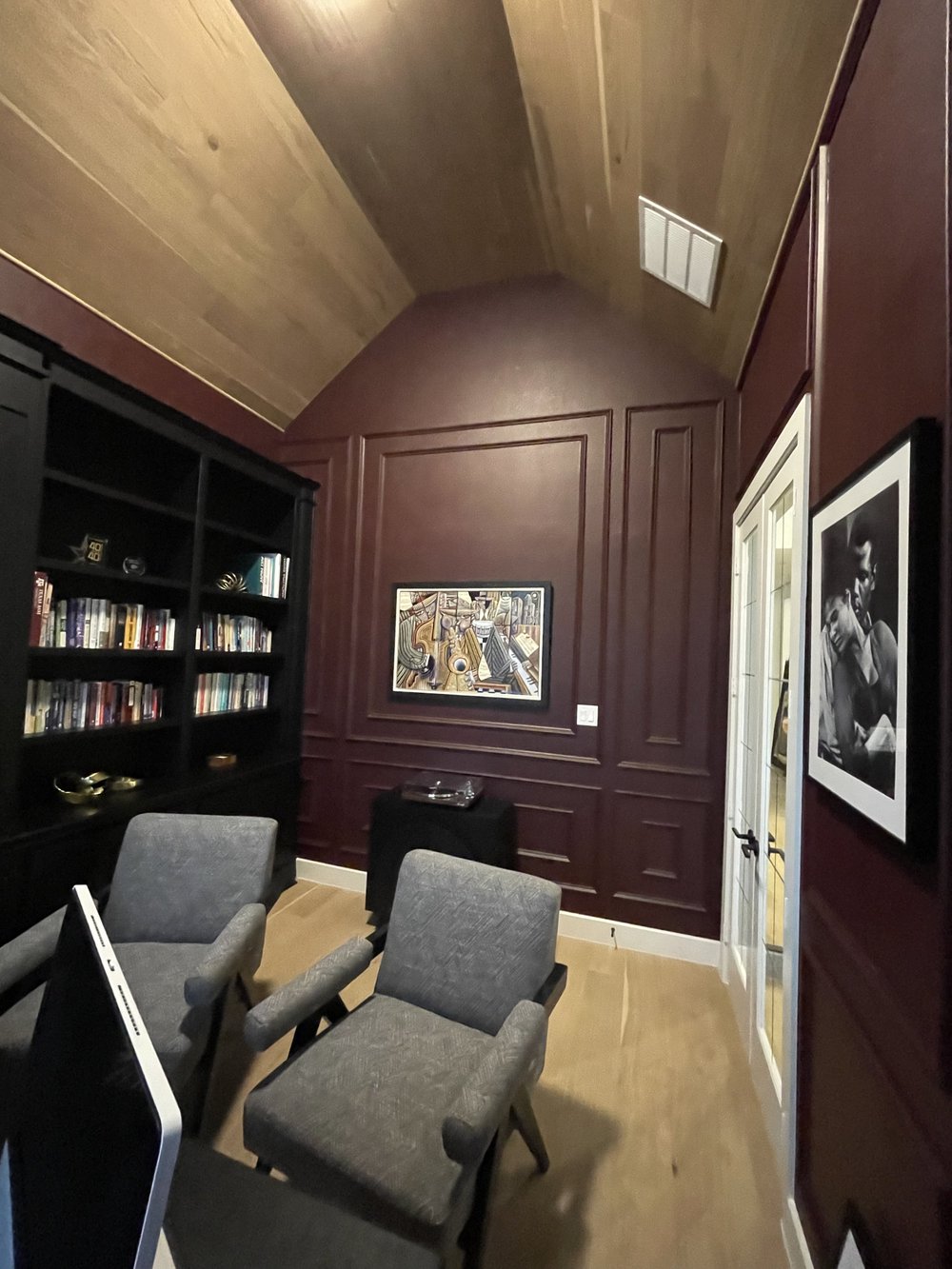 Study with oxblood panelled walls, a wood plank ceiling and black built-in shelving
