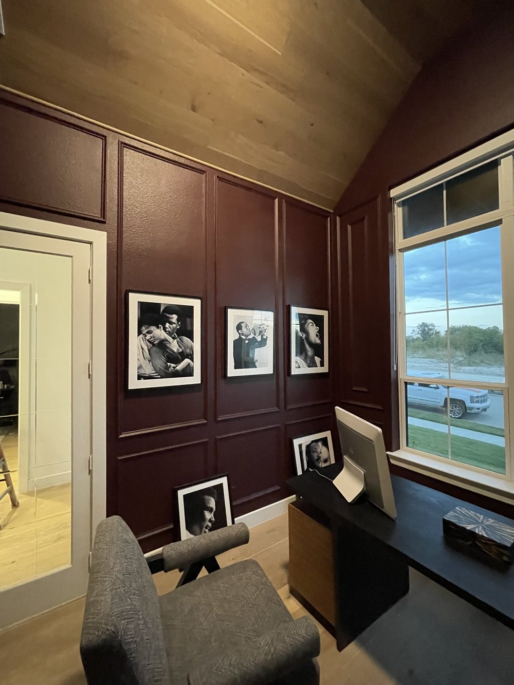 Oxblood panelled office wall hung with black and white portraits beside the window