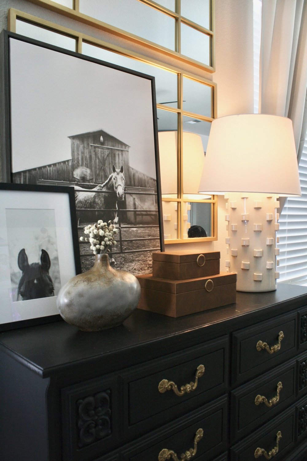Black dresser topped with a lamp, a framed barn photograph and copper boxes