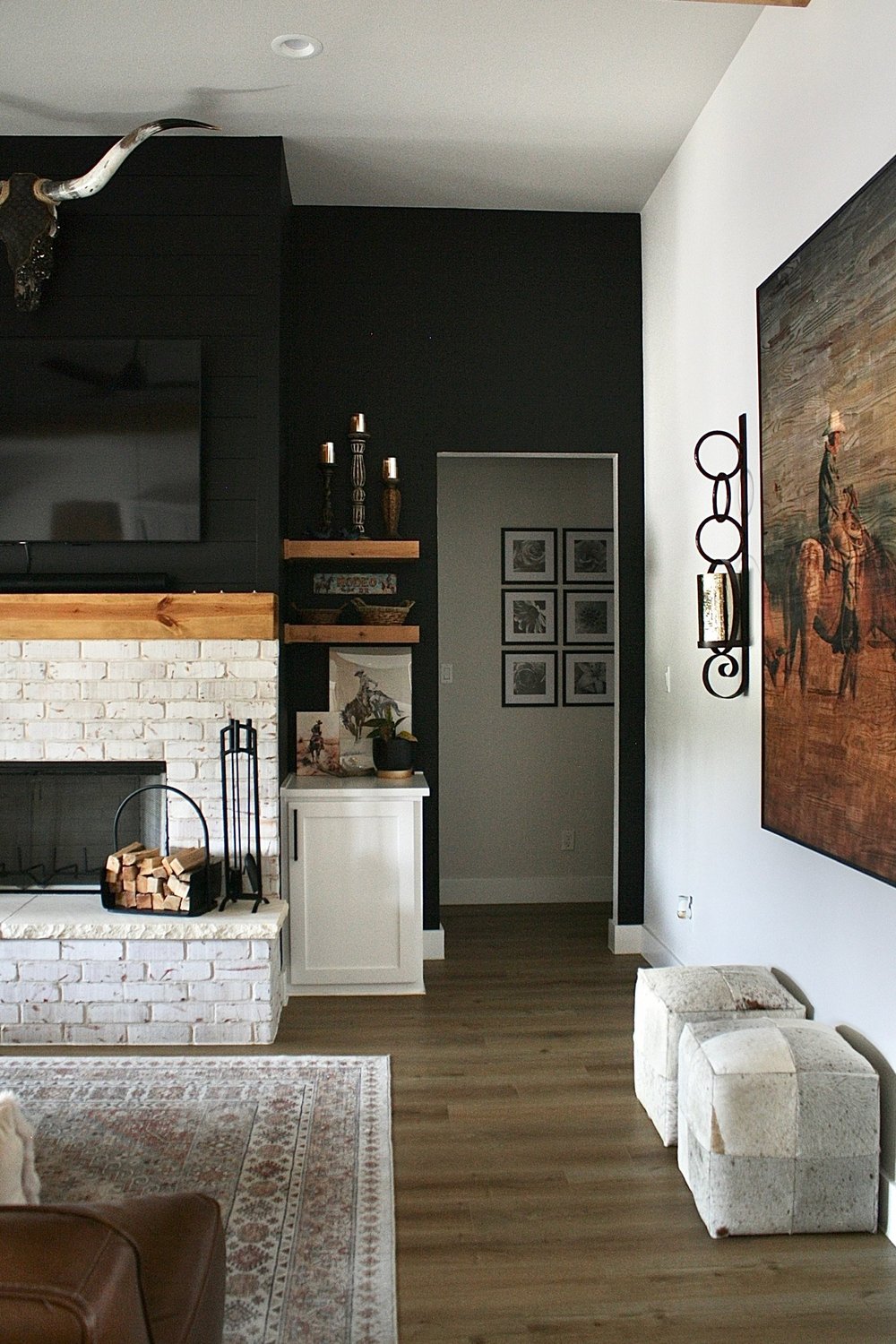 Living room from the sofa showing the black accent wall, floating shelves and checked ottomans