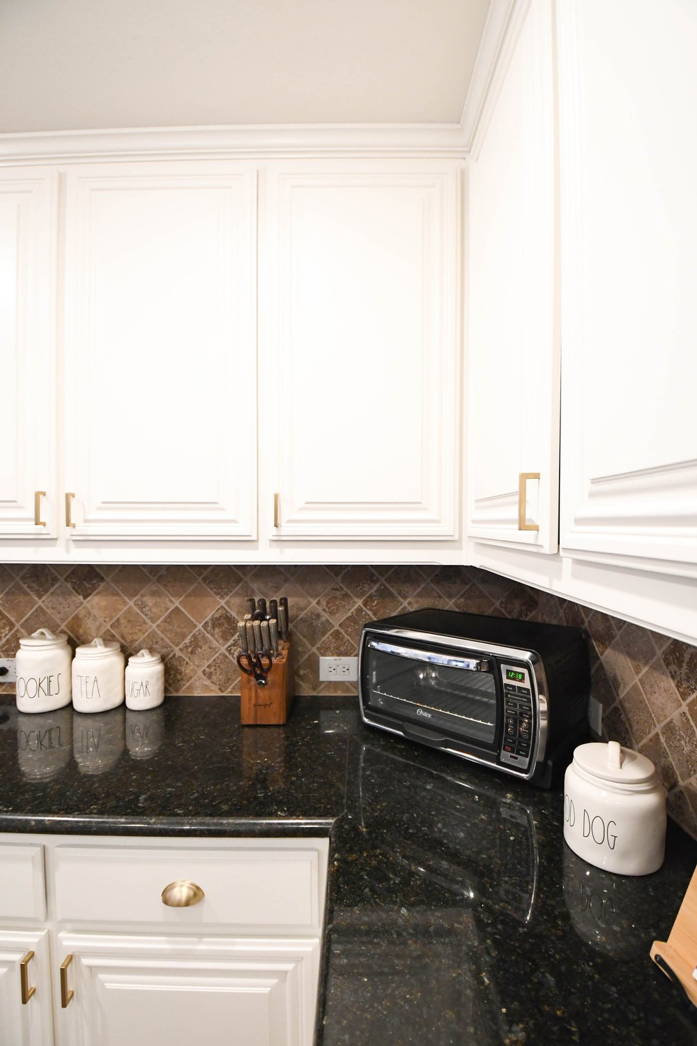 White kitchen cabinets and a black granite counter with a tile backsplash