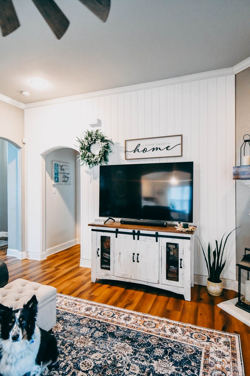 Living room with a TV on a barn door console against a white plank wall