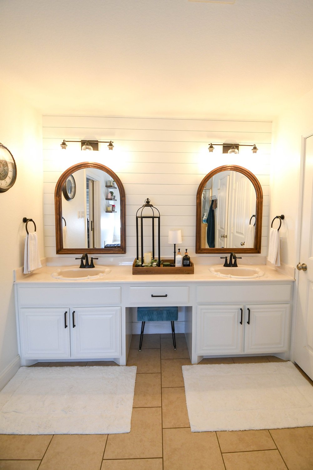 Double vanity with two arched wood mirrors on a shiplap wall