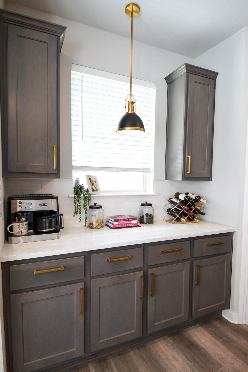 Coffee bar run of stained oak cabinets with a brass pendant over the counter