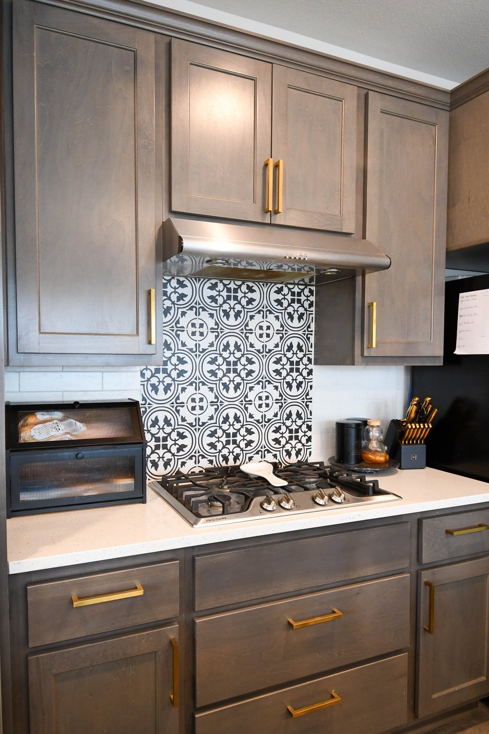 Patterned tile backsplash behind the cooktop under the hood cabinet