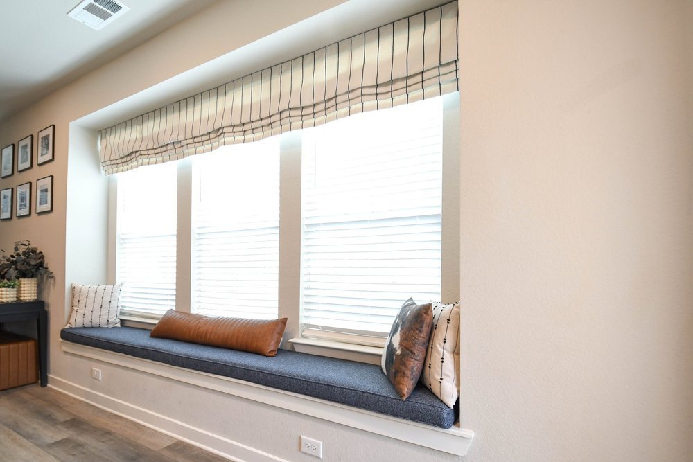 The window bench along the bay window with its striped valance