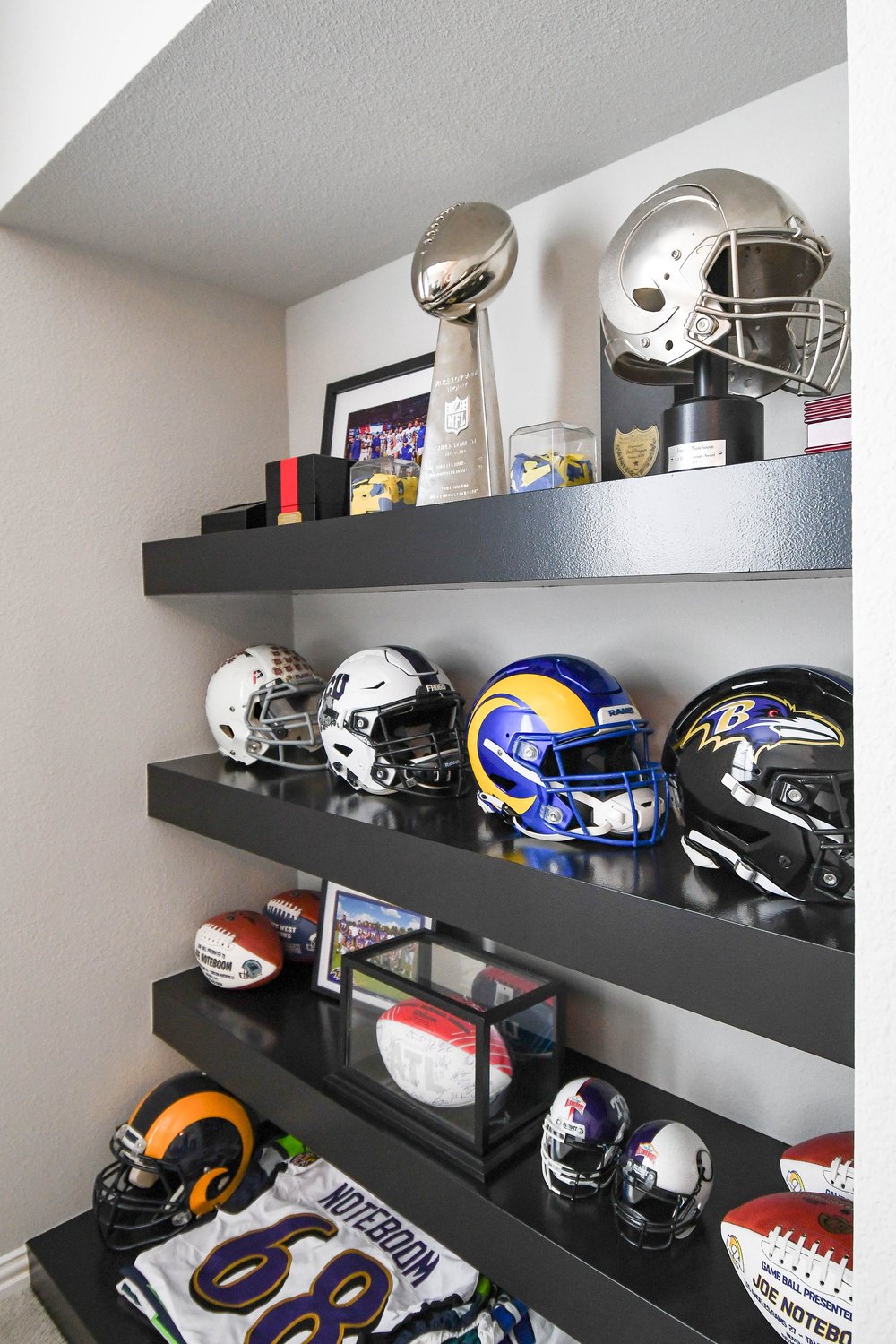 Close view of the shelves with a trophy replica, chrome helmet and signed footballs