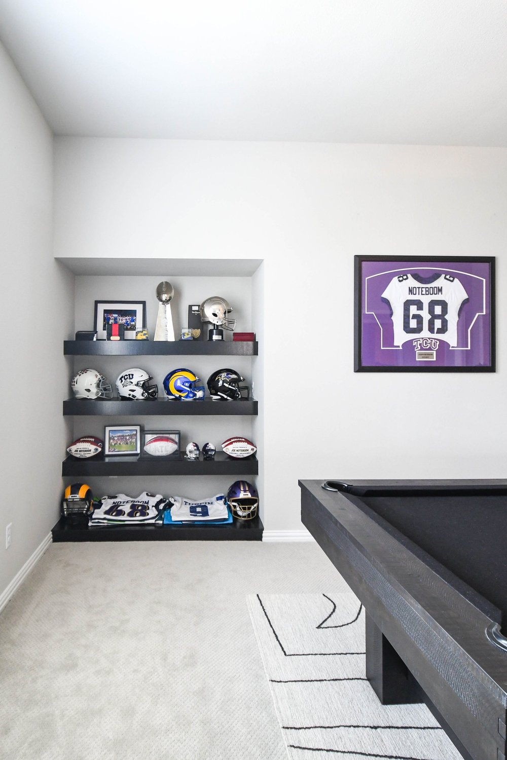 Pool table and the display niche with a framed purple jersey on the wall