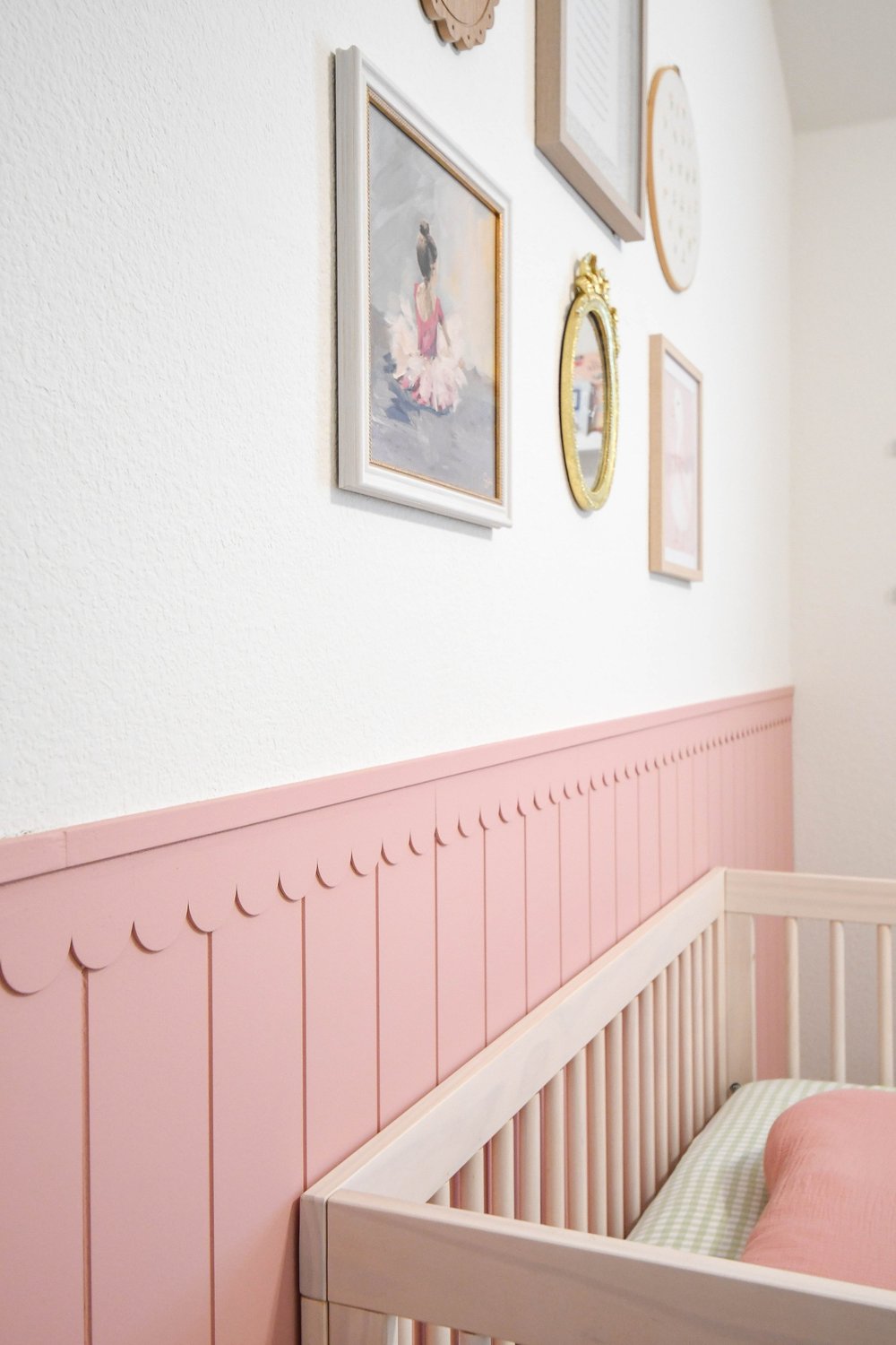 Corner of the nursery with framed ballet prints above the pink panelling and crib