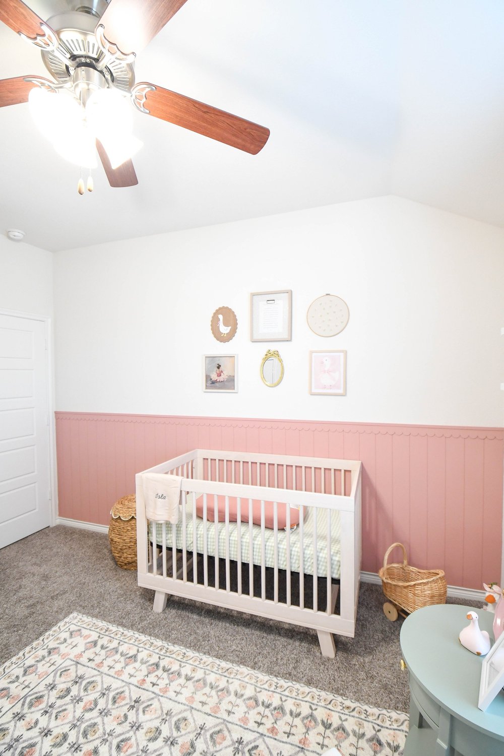 The crib and gallery wall from the doorway with a mint side table at the right