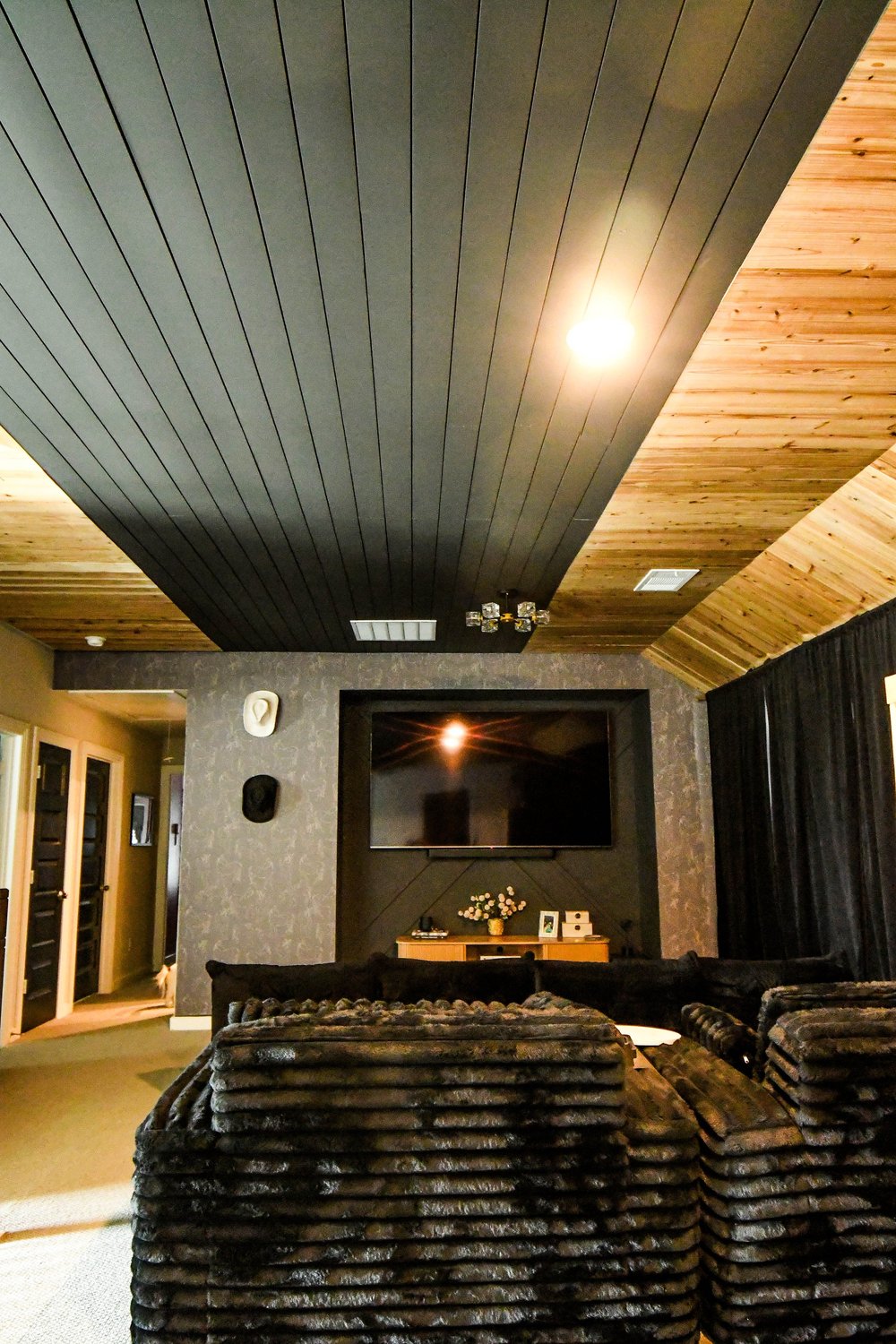 Media loft with a black plank ceiling, cedar barrel vault and a wall mounted TV