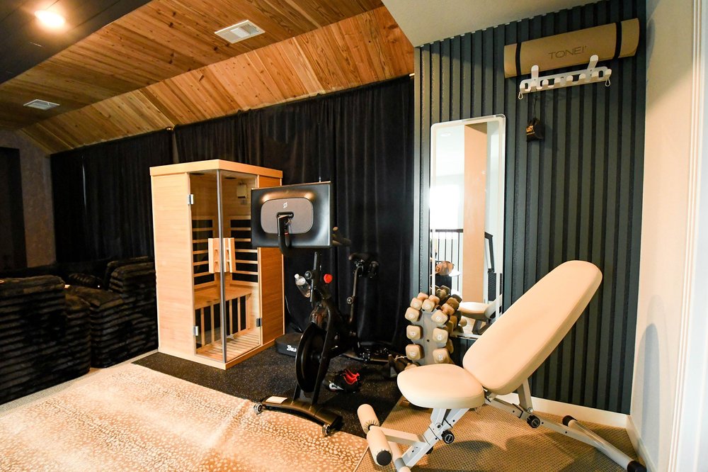 Gym with an infrared sauna cabin, bike and bench under the cedar vaulted ceiling