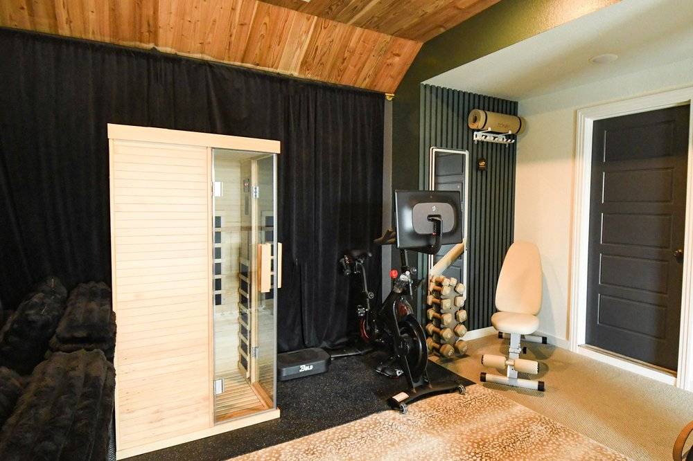 Infrared sauna beside the exercise bike with the blackout curtain drawn back