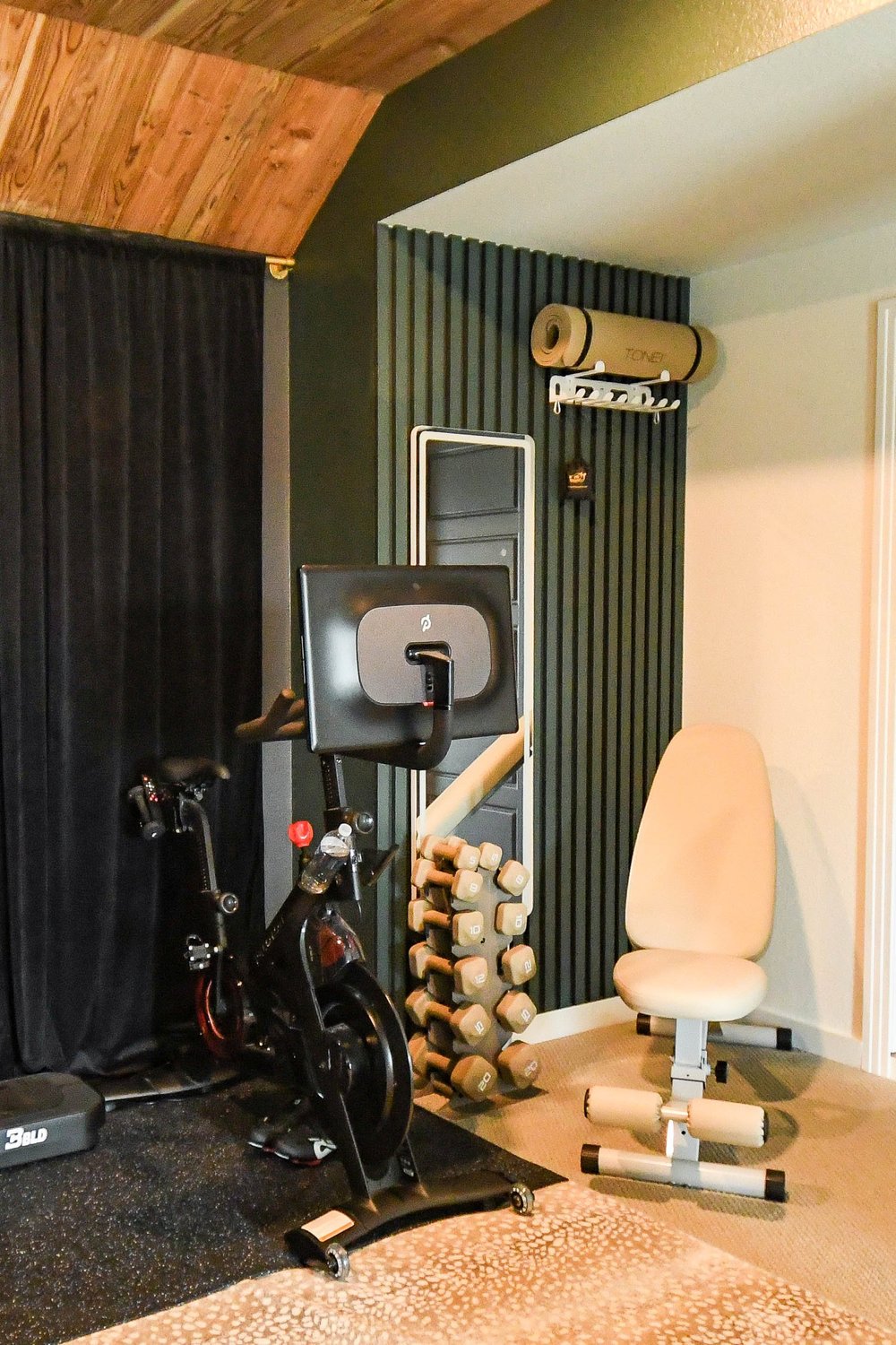 Exercise bike, dumbbell rack and bench with a yoga mat holder above