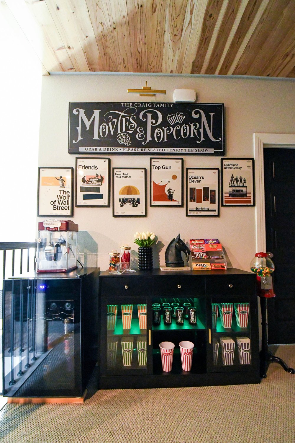 The concession area with a backlit cabinet of popcorn boxes and a drinks fridge