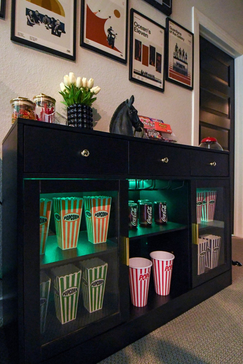 The lit cabinet shelves of popcorn boxes and striped cups