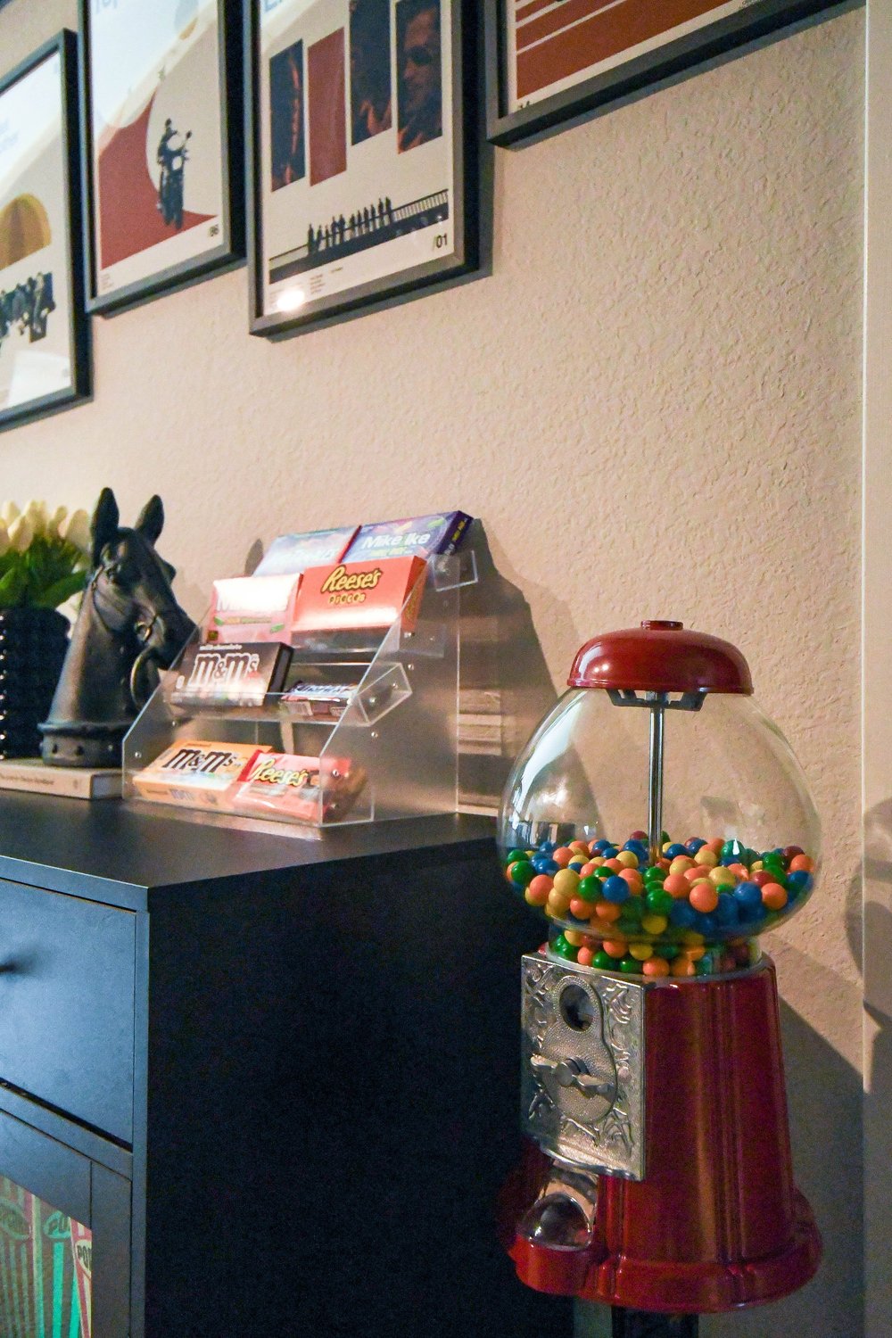 Red gumball machine beside the candy rack under the film posters