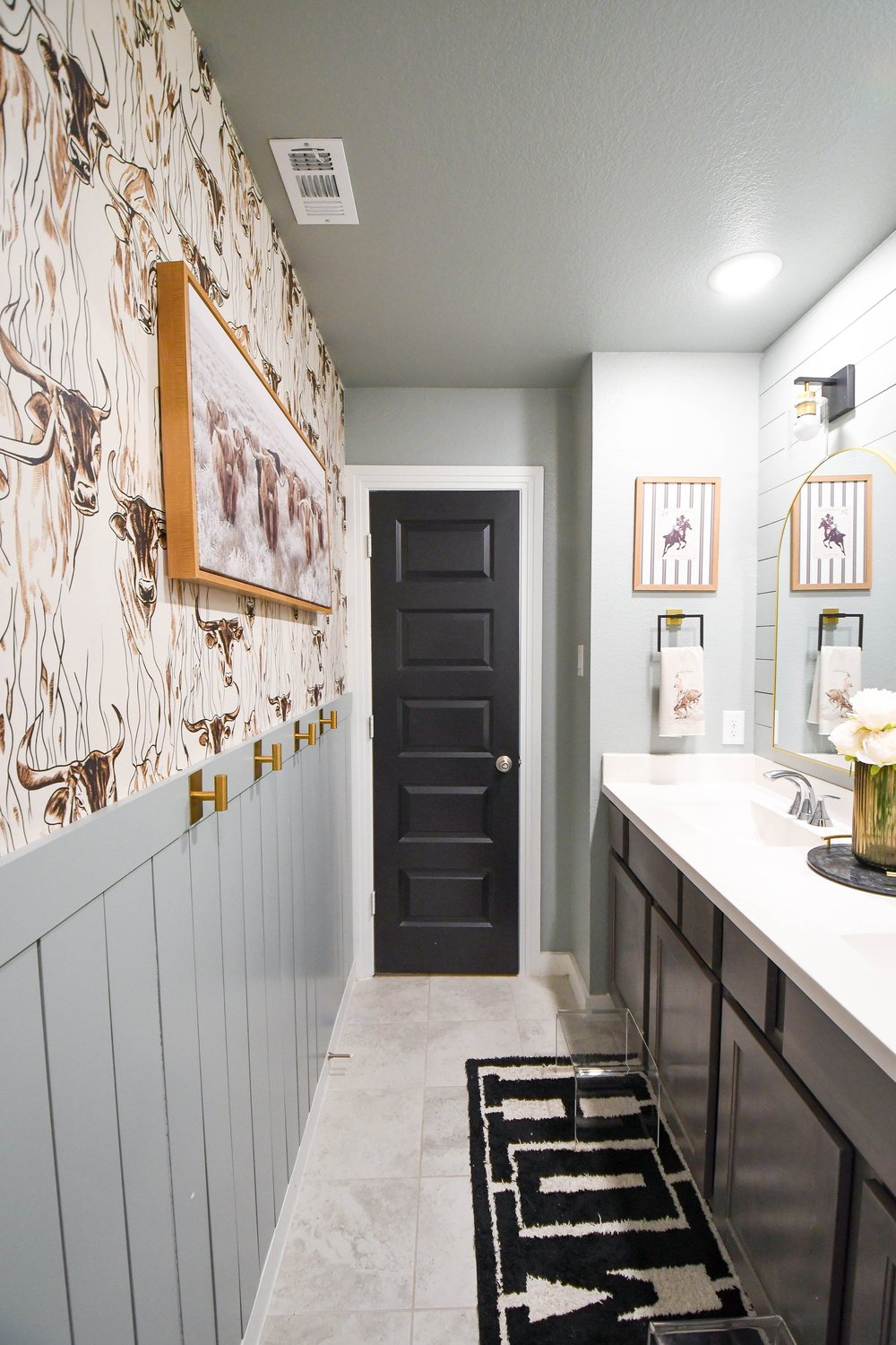 Wallpapered wall and vanity with the patterned rug on the tile floor