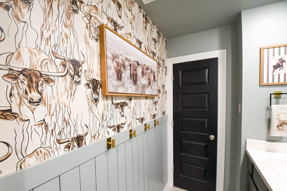 The wallpaper's longhorn pattern with the framed canvas above the wainscot