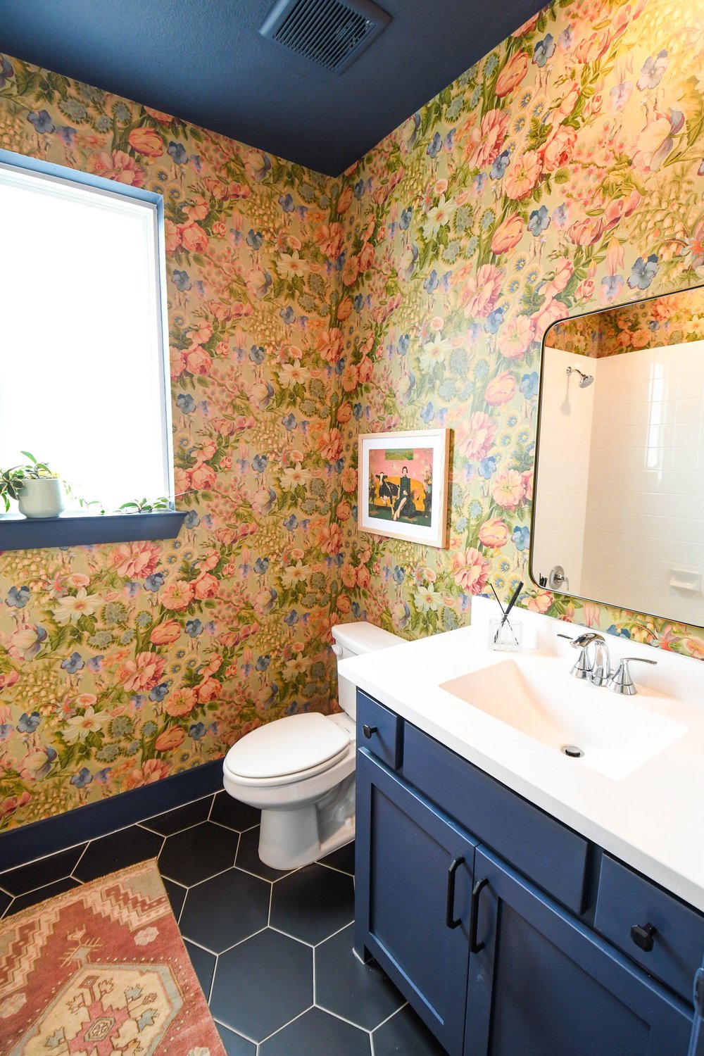 Navy vanity and toilet on black hexagon tile with a patterned runner