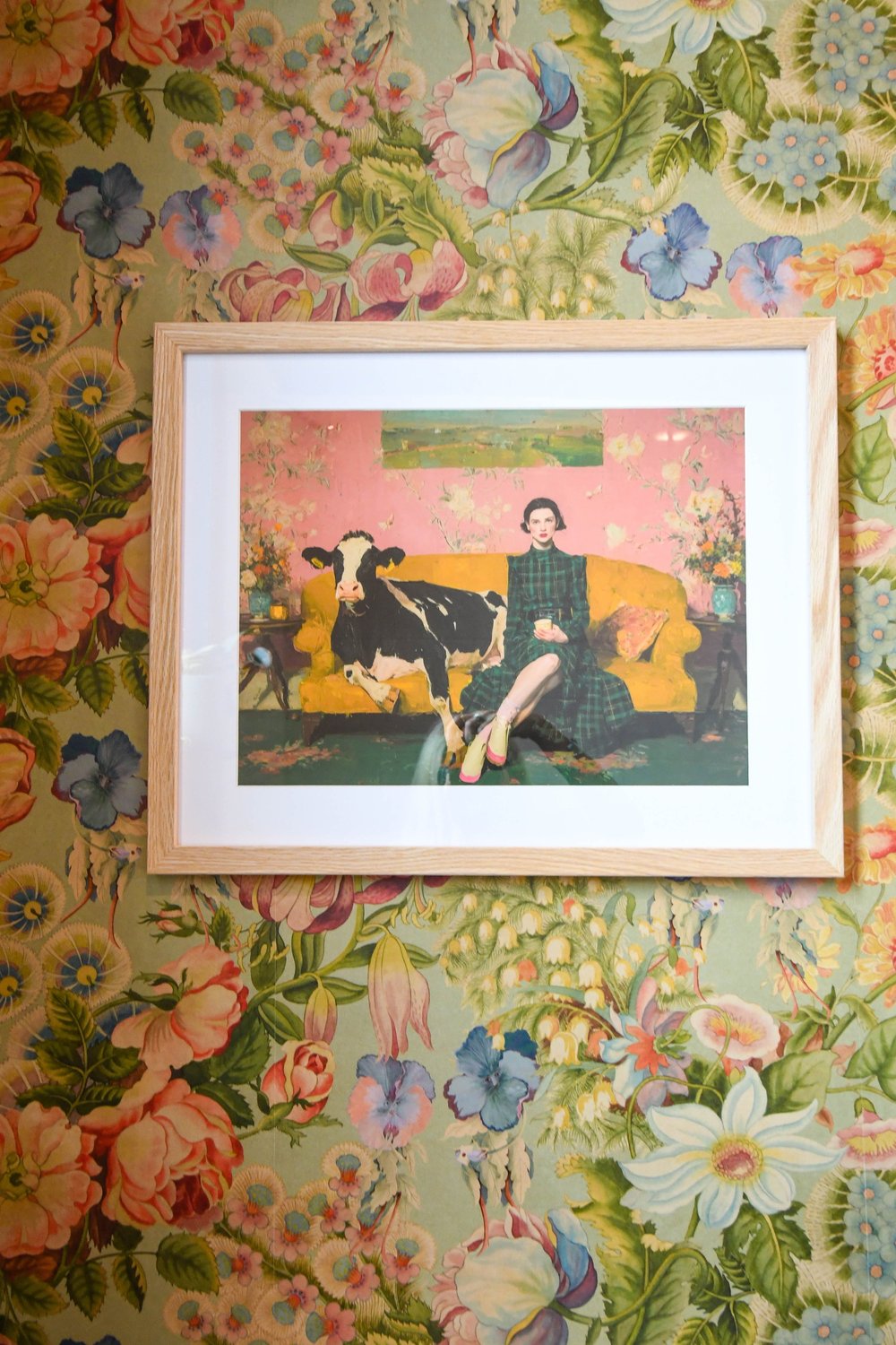 The framed cow print centred on the wildflower wallpaper
