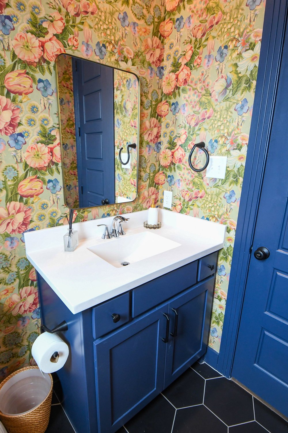 Navy vanity with a black framed mirror seen past the open navy door